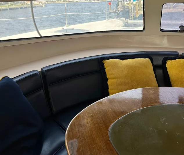 Felice Yacht Photos Pics Interior of 1998 Fountaine Pajot Athena 38 yacht with cushioned seating and wooden table.