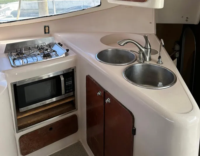 Felice Yacht Photos Pics Compact kitchen area in a 1998 Fountaine Pajot Athena 38 catamaran with stove, microwave, and dual sinks.
