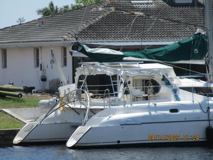 Felice Yacht Photos Pics 1998 Fountaine Pajot Athena 38 catamaran docked near a house, with green sail cover.