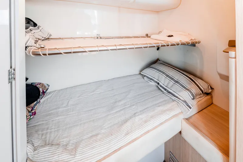 Viakarey Yacht Photos Pics Compact cabin bunk bed in 2023 Sirena 58 yacht, featuring striped bedding and storage shelf.