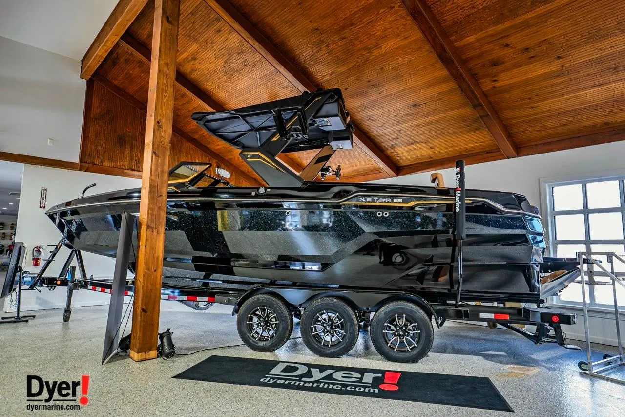 2026 MasterCraft XStar 25 boat on trailer in showroom, featuring sleek black design.