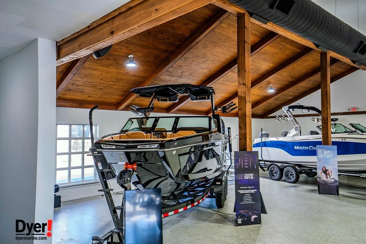 2026 MasterCraft XStar 25 boat displayed in a showroom with wooden ceiling.