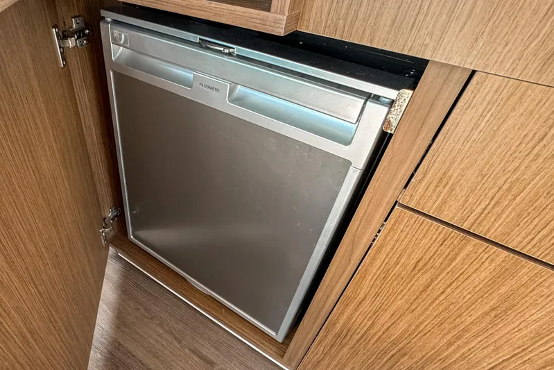  Yacht Photos Pics Built-in fridge on 2025 Beneteau Antares 9 yacht, featuring sleek wood cabinetry.