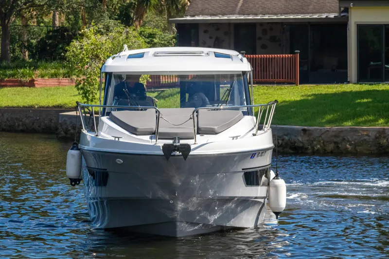  Yacht Photos Pics 2025 Beneteau Antares 9 cruising on a calm river near a house.