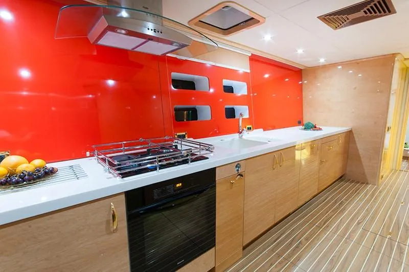 Houbara Yacht Photos Pics Luxurious kitchen interior of 2012 Sunreef 82 DD yacht with vibrant red backsplash.