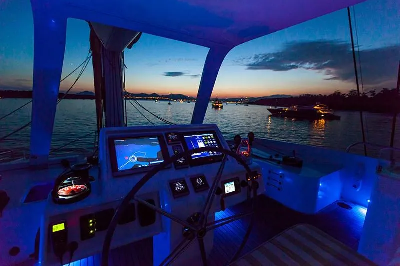 Houbara Yacht Photos Pics Cockpit view of 2012 Sunreef 82 DD yacht at sunset, featuring illuminated controls and serene waters.