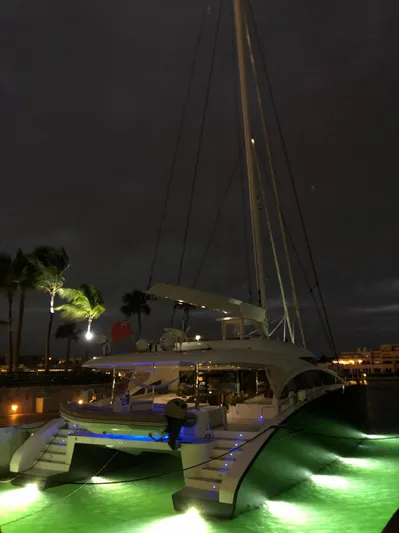 Houbara Yacht Photos Pics Luxurious 2012 Sunreef 82 DD yacht illuminated at night, docked with glowing green water.