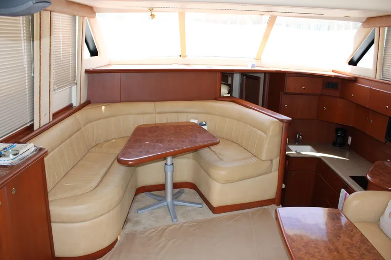 Worth The Wake Yacht Photos Pics Interior of 2006 Silverton 42 Convertible yacht with beige seating and wooden table.