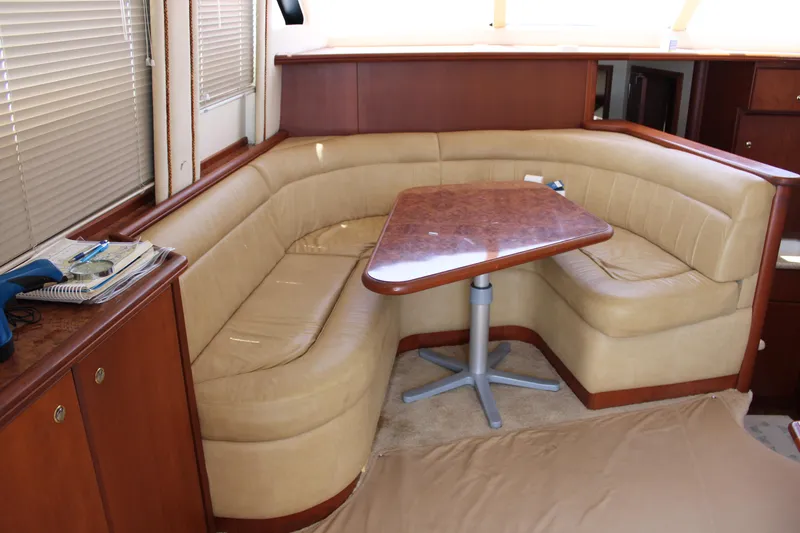 Worth The Wake Yacht Photos Pics Luxurious interior of 2006 Silverton 42 Convertible yacht with beige seating and wooden table.