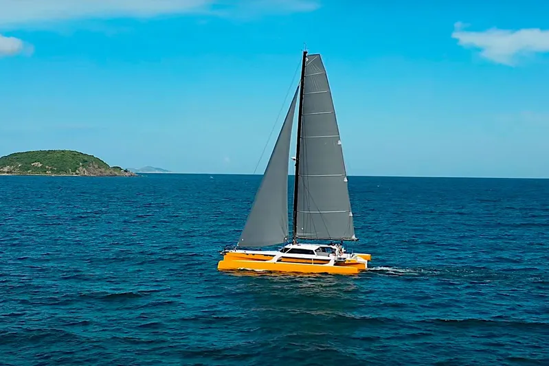  Yacht Photos Pics 2026 Rapido 60 catamaran sailing on open sea with island in background.
