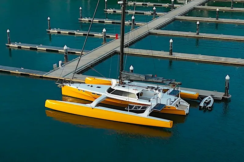  Yacht Photos Pics 2026 Rapido 60 trimaran docked in a marina with vibrant yellow hulls.