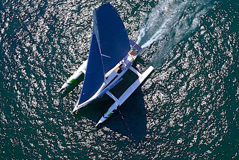  Yacht Photos Pics Aerial view of 2026 Rapido 60 trimaran sailing on sparkling water.