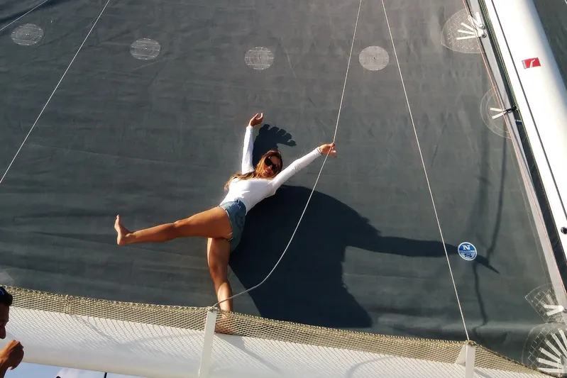  Yacht Photos Pics Woman posing on a Rapido 60 sailboat, 2026 model, with large sail backdrop.