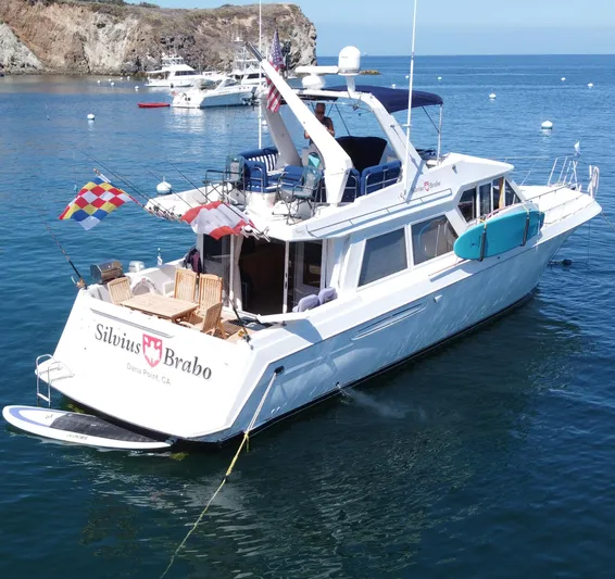 Silvius Brabo Yacht Photos Pics 2000 Navigator 53 Classic yacht anchored in scenic bay with flags and paddleboard.