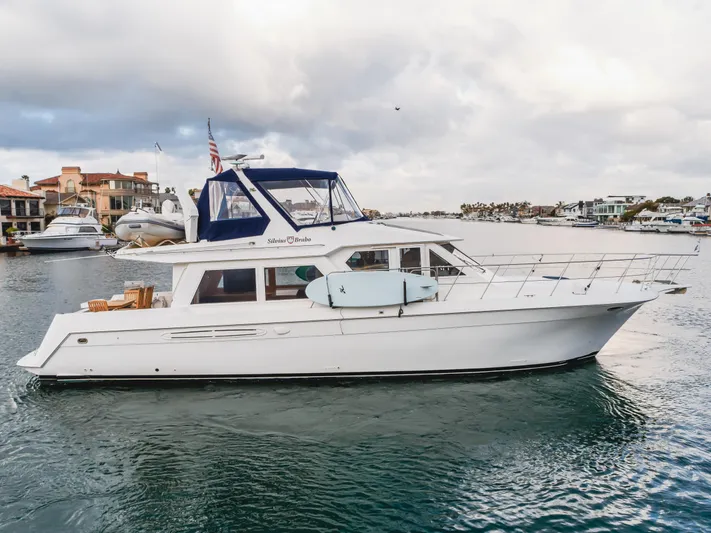 Silvius Brabo Yacht Photos Pics Navigator 53 Classic yacht from 2000 on calm water, with coastal homes in the background.