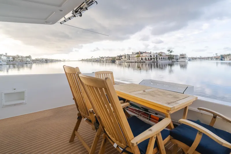 Silvius Brabo Yacht Photos Pics Deck view from 2000 Navigator 53 Classic yacht, featuring wooden chairs and serene waterfront scenery.