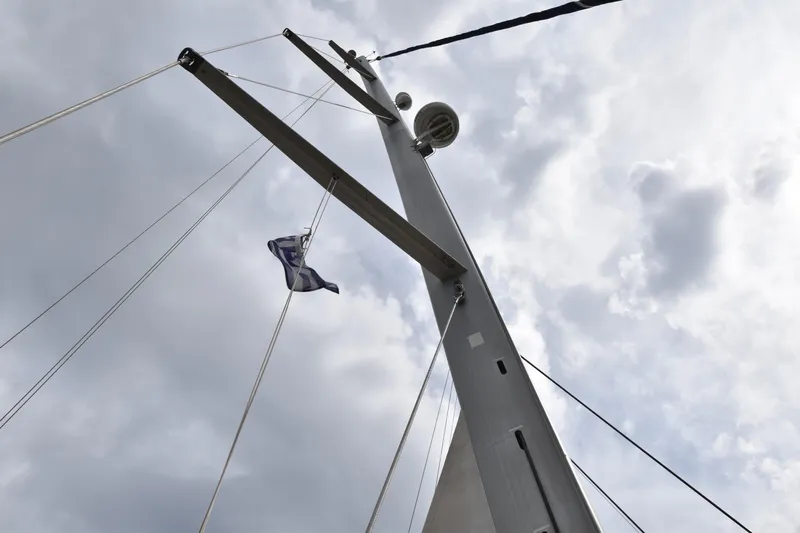 Artemis Yacht Photos Pics Mast of 2004 Beneteau 57 sailboat against cloudy sky, featuring a flag.