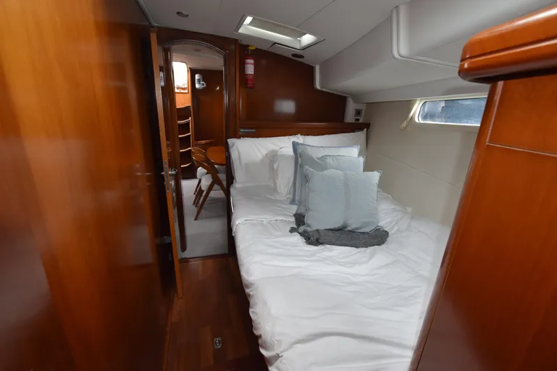 Artemis Yacht Photos Pics Luxurious cabin interior of a 2004 Beneteau 57 yacht with cozy bedding and wooden finishes.