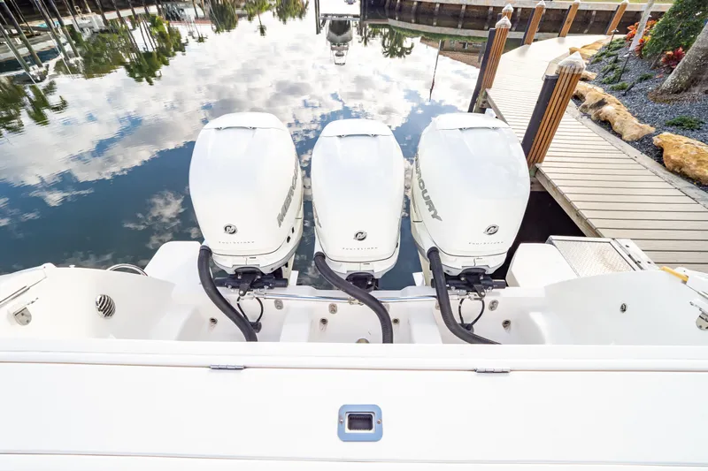  Yacht Photos Pics Triple Mercury outboard engines on a 2019 Intrepid 407 Cuddy boat docked by a wooden pier.
