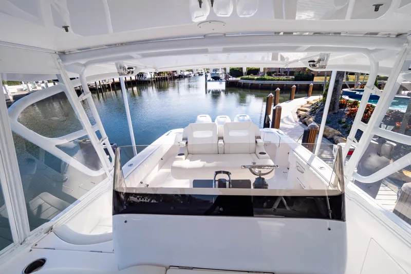  Yacht Photos Pics 2019 Intrepid 407 Cuddy boat interior with seating, docked by a scenic waterfront.