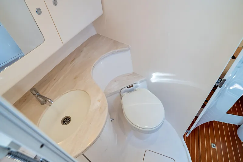 Yacht Photos Pics 2019 Intrepid 407 Cuddy bathroom with sink and toilet, featuring wooden flooring.