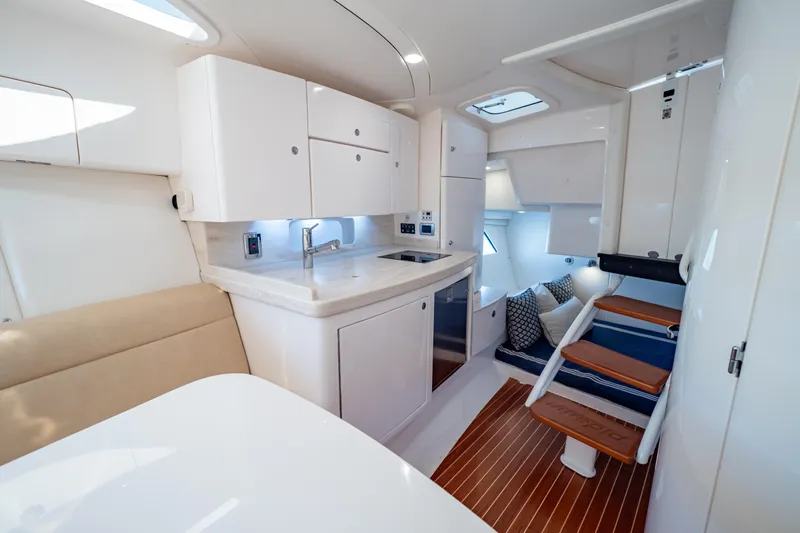  Yacht Photos Pics 2019 Intrepid 407 Cuddy interior with modern kitchen, seating, and wooden steps.