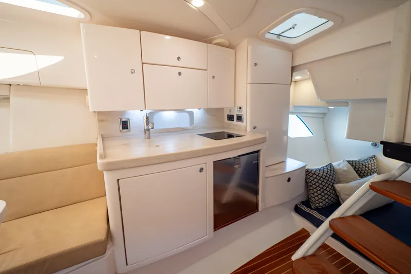  Yacht Photos Pics Luxurious interior of 2019 Intrepid 407 Cuddy boat with modern kitchenette and seating area.