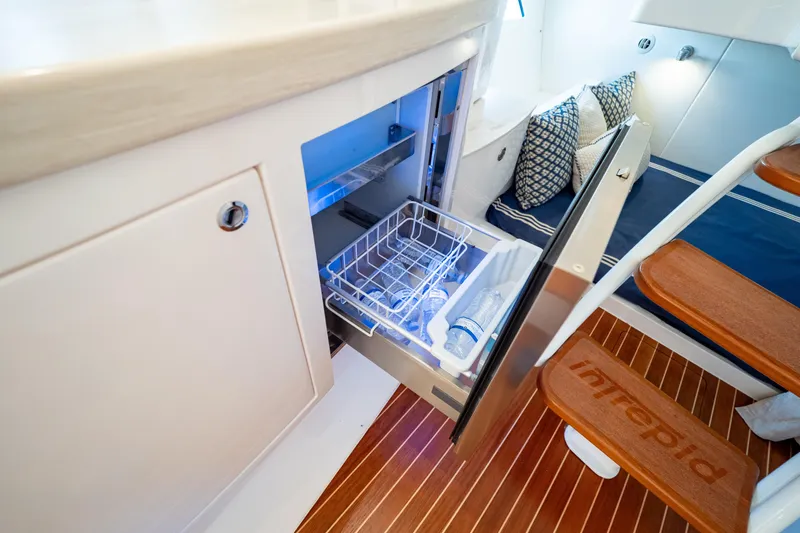  Yacht Photos Pics 2019 Intrepid 407 Cuddy interior with open fridge, wooden steps, and cushions.