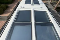 2020 Nimbus 405 Coupé boat with sleek rooftop solar panels, docked near lush greenery.