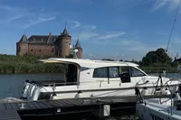 Nimbus 405 Coupé 2020 yacht docked near a historic castle under a clear blue sky.