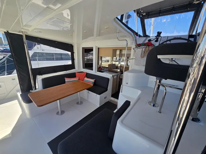 Encore Yacht Photos Pics 2021 Lagoon 40 catamaran interior with seating area, table, and helm station.