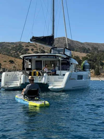 Encore Yacht Photos Pics 2021 Lagoon 40 catamaran anchored near scenic coastline with person on paddleboard.