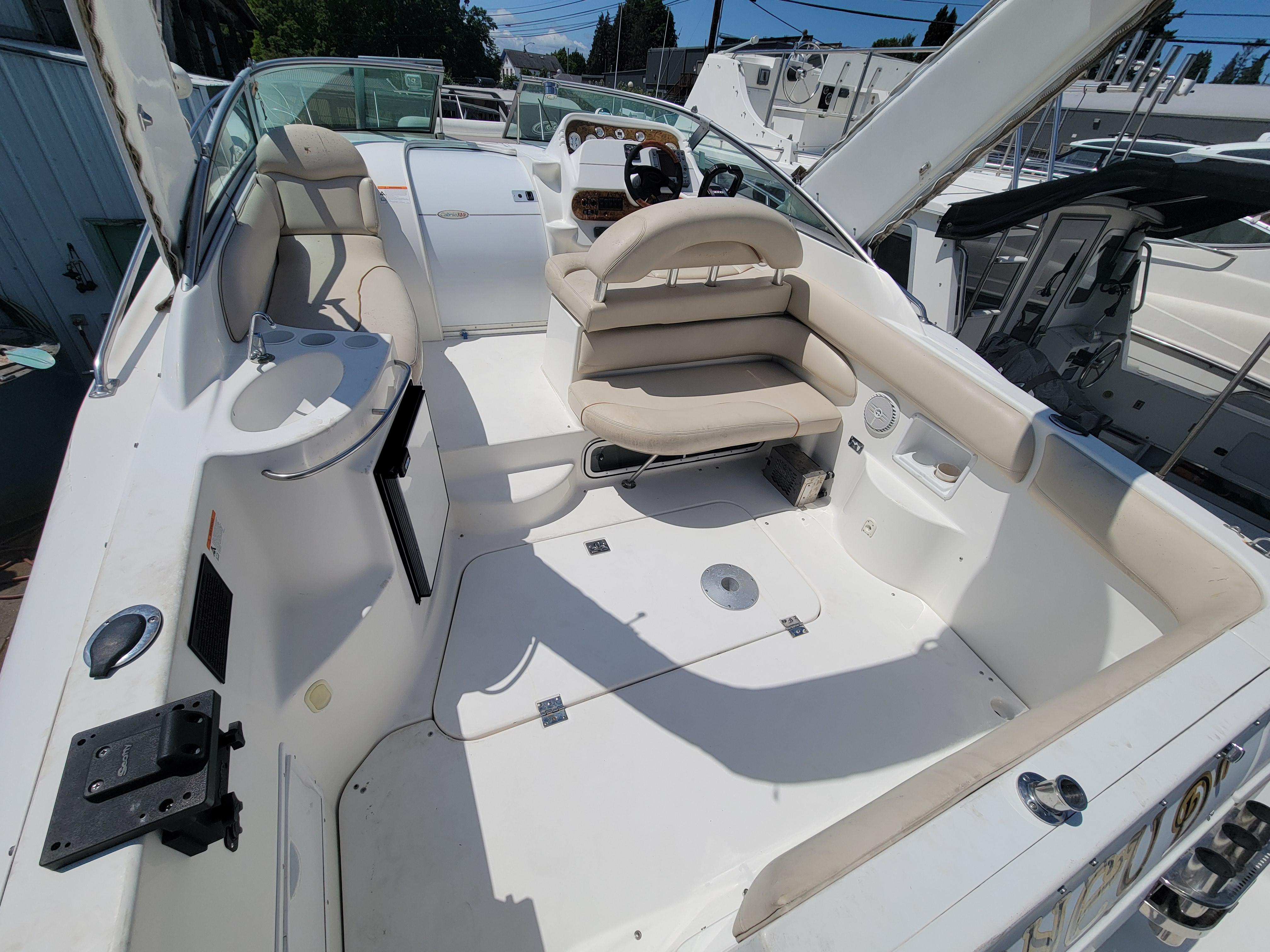 2003 Larson 310 boat interior with seating and steering wheel, docked in a marina.