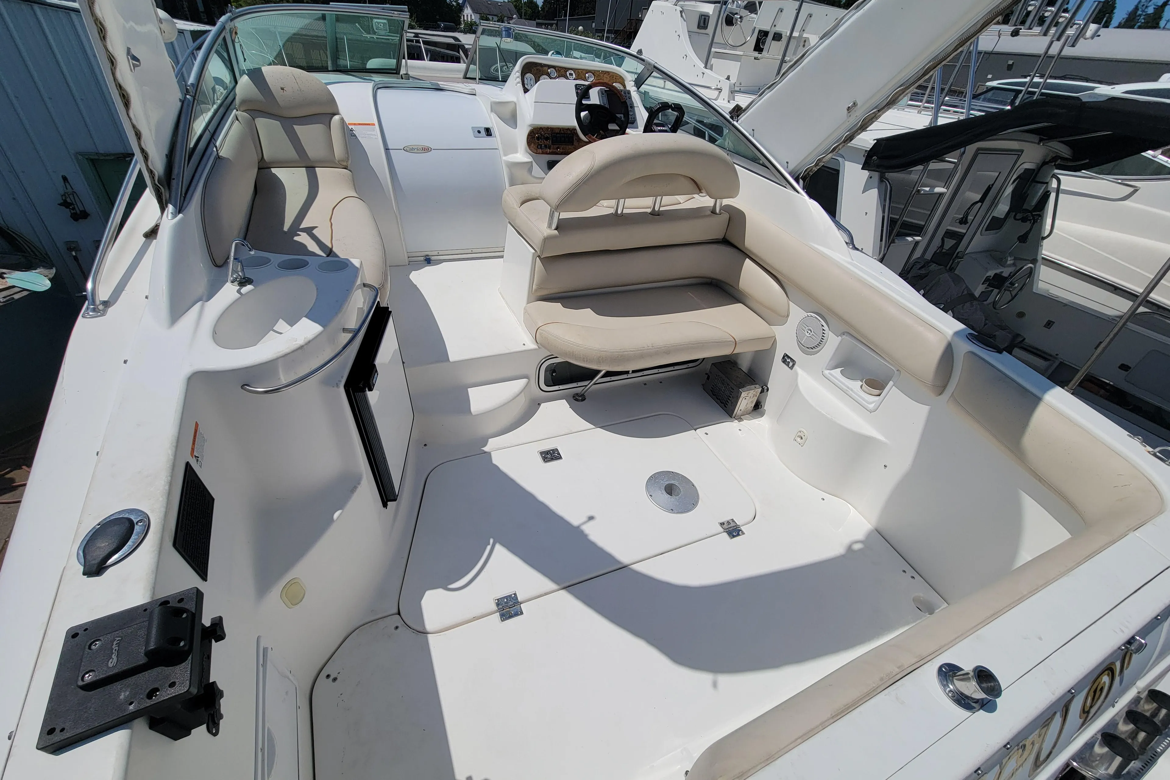 2003 Larson 310 boat interior with seating and steering wheel, docked in a marina.