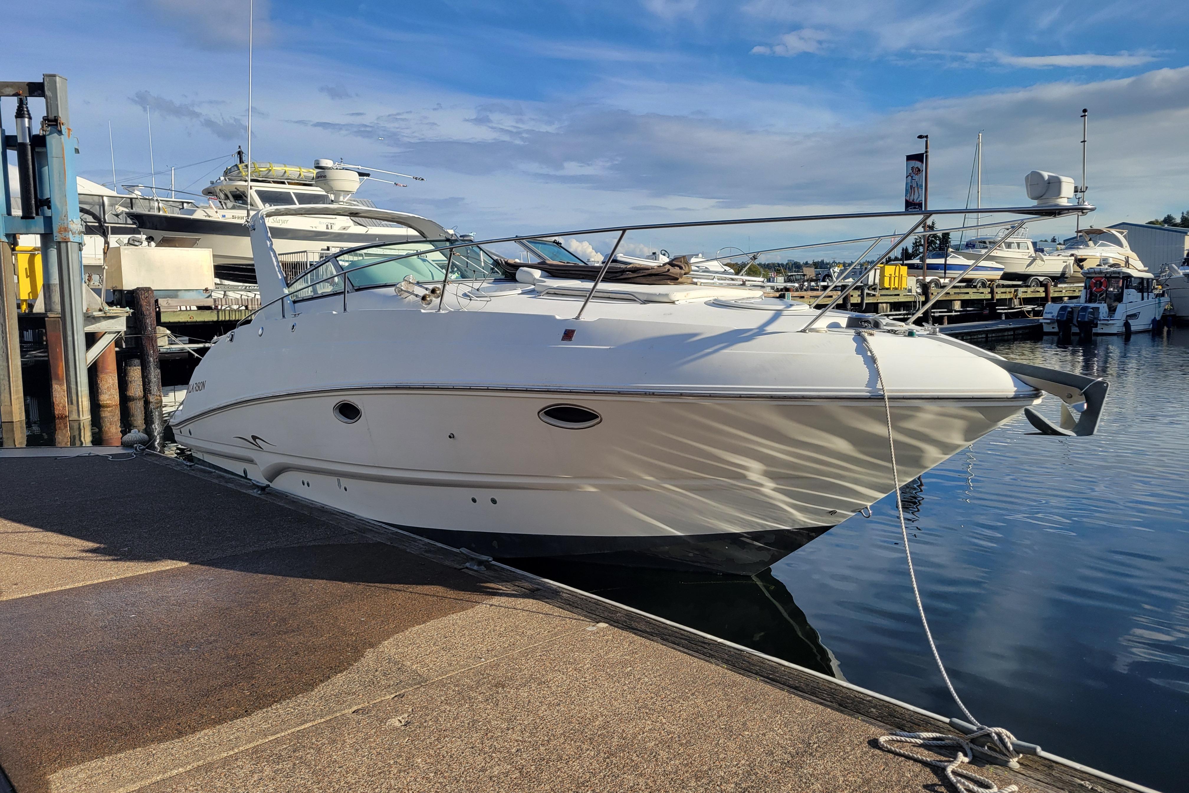 2003 Larson 310 boat docked at marina under clear blue sky.
