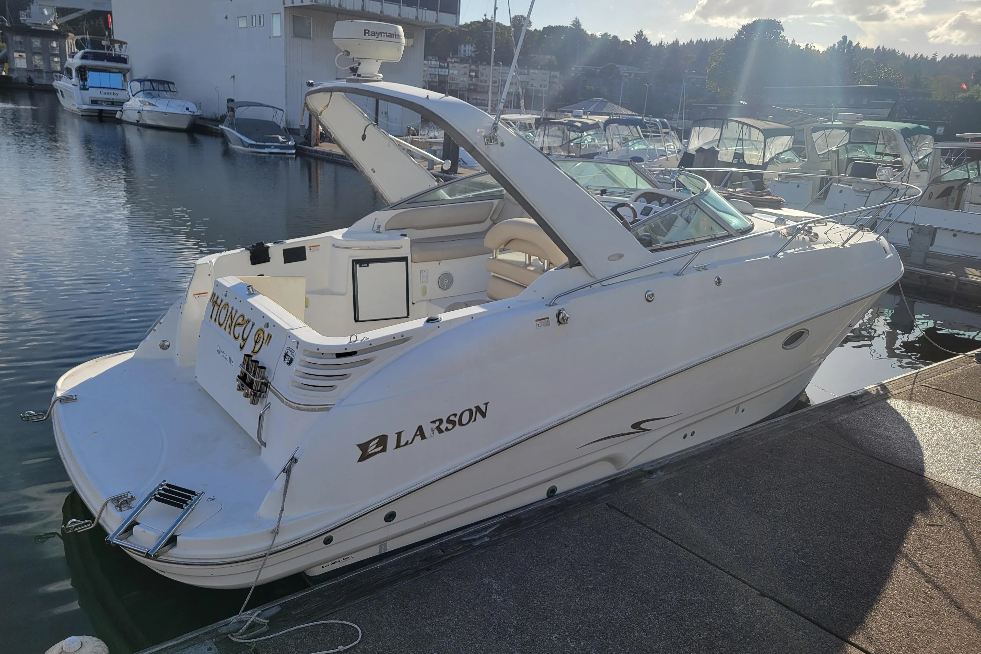 2003 Larson 310 boat docked at marina under sunny sky.