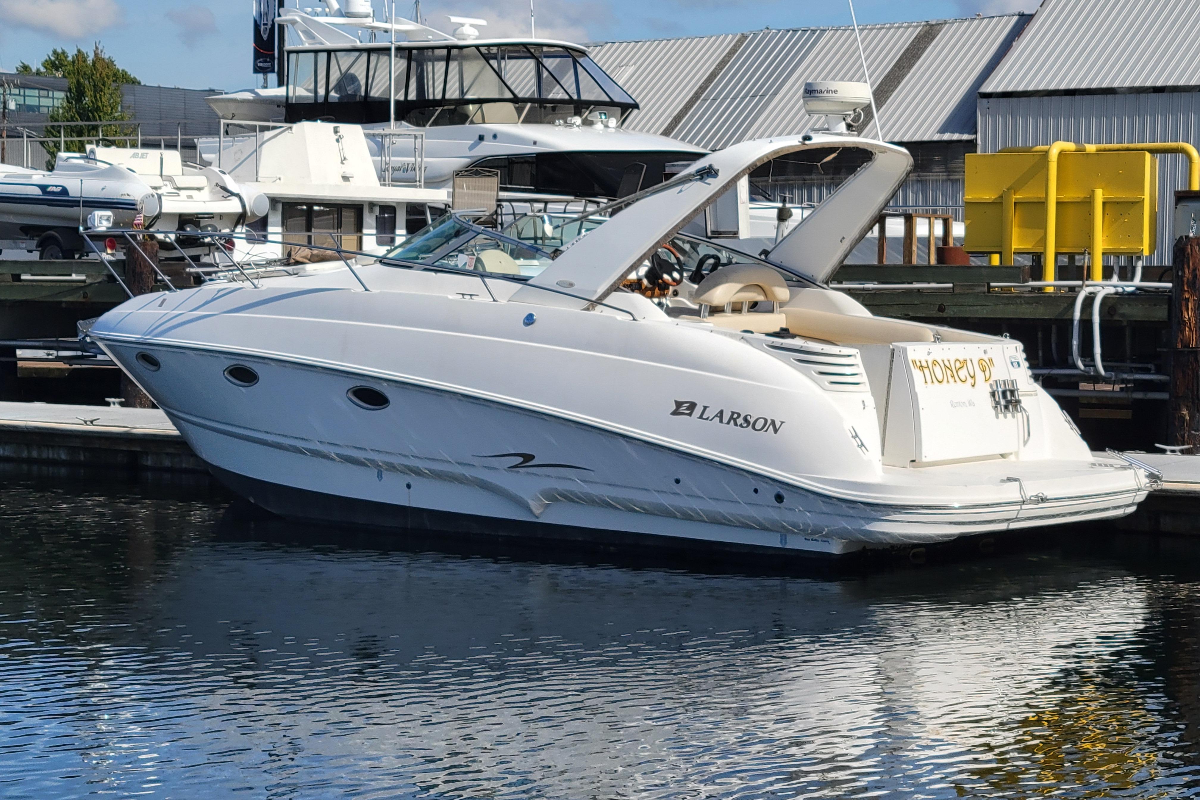 2003 Larson 310 boat docked at marina, reflecting on calm water.