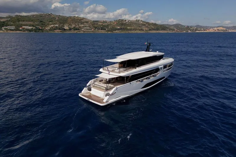 Yacht Photos Pics Luxurious 2025 Ferretti Yachts INFYNITO 90 cruising on open sea, scenic coastal backdrop.