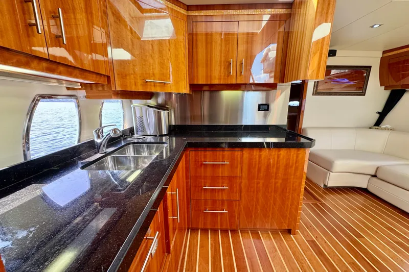 Makin' Waves II Yacht Photos Pics Luxurious kitchen interior of 2011 Regal 52 Sport Coupe yacht with wood cabinetry and black countertops.