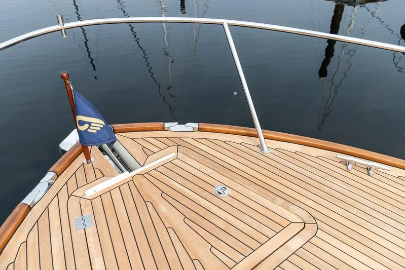 Kite Yacht Photos Pics Hinckley Talaria 43 (2014) yacht deck with wooden finish and flag, docked on calm water.