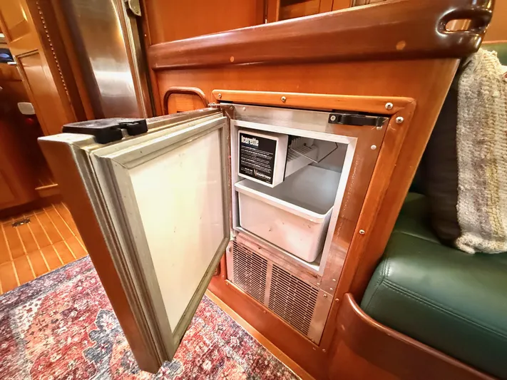 Bluepearl Yacht Photos Pics Open refrigerator in 2006 Passport Vista 515CC yacht interior, featuring wooden cabinetry and a colorful rug.