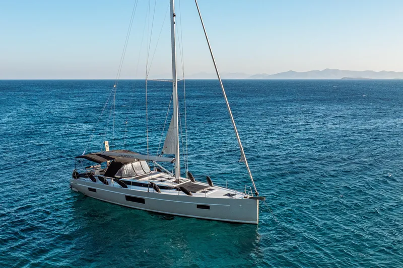  Yacht Photos Pics Sailing yacht Bavaria C57 2022 on open sea with distant mountains.