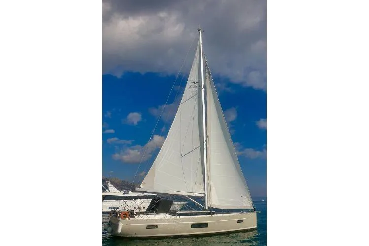  Yacht Photos Pics 2022 Bavaria C57 sailboat with white sails on a calm sea under a cloudy sky.