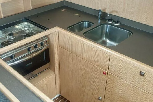  Yacht Photos Pics Modern kitchen in 2022 Bavaria C57 yacht with stove, sink, and wooden cabinetry.