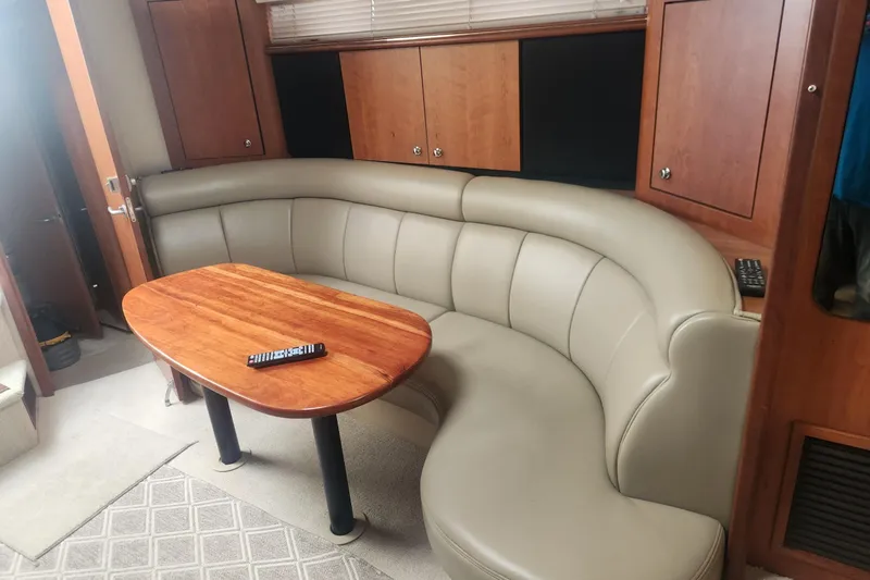 Bella Vita Yacht Photos Pics Interior of 2002 Cruisers Yachts 3870 Express with curved leather seating and wooden table.