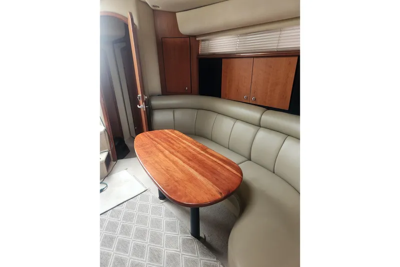 Bella Vita Yacht Photos Pics Interior of 2002 Cruisers Yachts 3870 Express with curved seating and wooden table.
