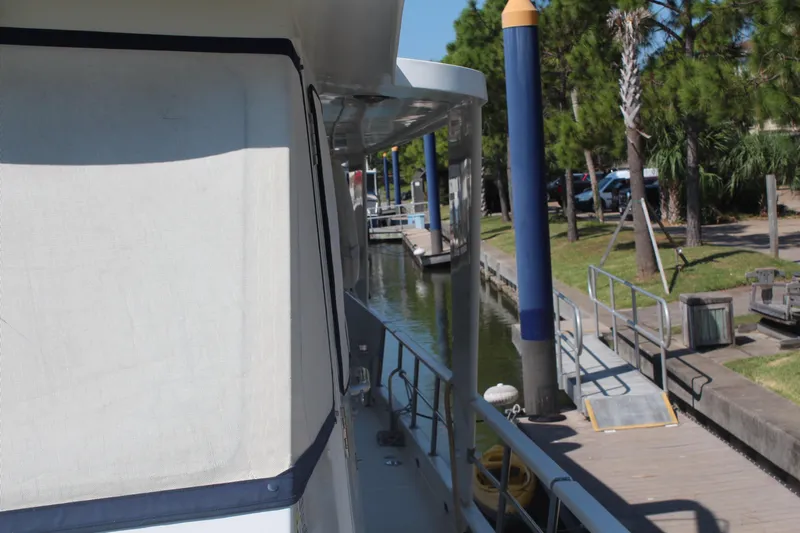 Gods Favor Yacht Photos Pics 1986 DeFever 53 yacht docked at a marina with trees and blue posts.