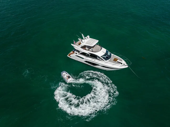 Dreams Yacht Photos Pics Aerial view of 2021 Sunseeker Manhattan 55 yacht with a small boat in turquoise water.
