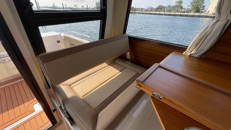  Yacht Photos Pics Interior of 2025 Ranger Tugs R-25 boat with seating and wooden table by the window.