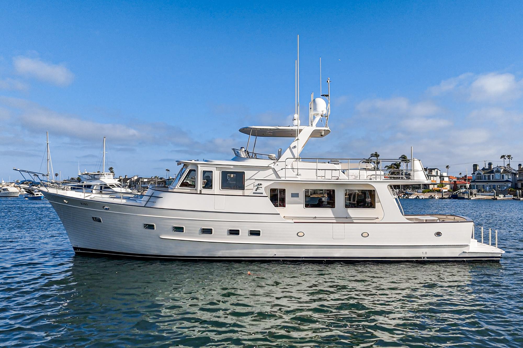 2018 Fleming 58 Pilothouse yacht on calm water under blue sky.